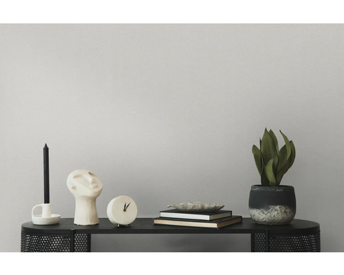 Dekorative Anordnung mit Kerze, Skulptur, Uhr, Büchern und Zimmerpflanze auf einem schwarzen Tisch