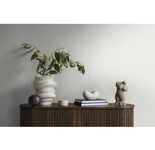 Dekoratives Arrangement mit Vase, Pflanzen, Büchern und Skulpturen auf einem Holzschrank