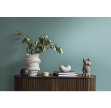 Dekorative Anordnung mit einer Vase, Büchern und einer Figur auf einem Holzschrank.