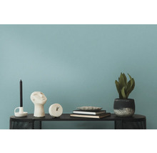 Dekorationsobjekte wie Kerze, Skulptur, Uhr, Bücher und Pflanze auf einem Tisch