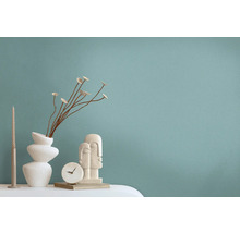 Dekorative Szene mit Vase, Trockenblumen, Kerze, Uhr und Skulptur auf einem Tisch.