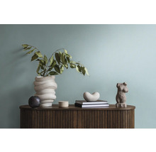 Dekoratives Interieur mit Vase, Skulpturen und Büchern auf einem Holzschrank.