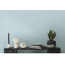 Dekorative Gegenstände wie Kerze, Skulptur, Uhr, Bücher und Zimmerpflanze auf einem Tisch