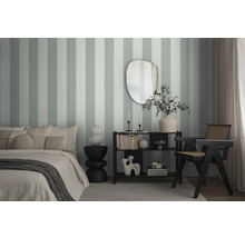 Schlafzimmer mit Bett, Beistelltisch, Regal und Stuhl vor einer gestreiften Wandtapete