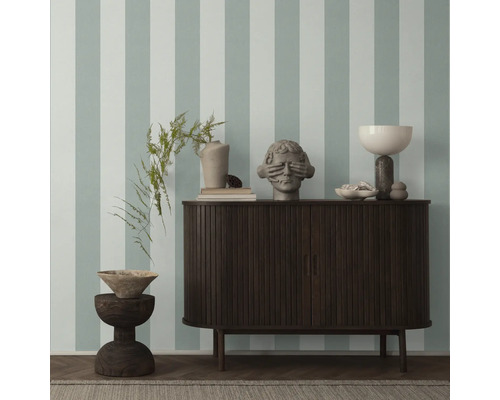 Einrichtungsgegenstände auf einem Sideboard vor einer Wand mit Streifenmuster.