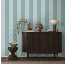 Wohnzimmer mit gestreifter Tapete, Sideboard und Dekorationsobjekten.