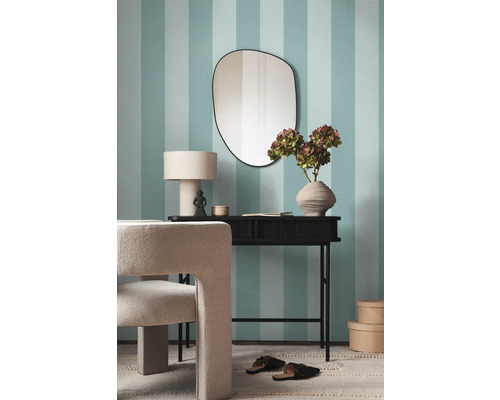 Einrichtungsgegenstände wie Spiegel, Tisch, Lampe, Dekoration und Stuhl vor einer blau-weiss gestreiften Wand.