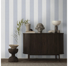 Wohnraum mit gestreifter Tapete, Kommode und Dekorationen.