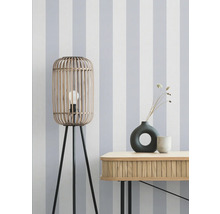 Dekorative Szene mit einer Stehlampe aus Holz, einer Kommode und Vasen vor einer gestreiften Tapete.