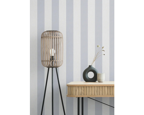 Dekorative Szene mit einer Stehlampe aus Holz, einer Kommode und Vasen vor einer gestreiften Tapete.