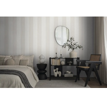 Schlafzimmer mit Bett, Regal, Sessel und gestreifter Tapete