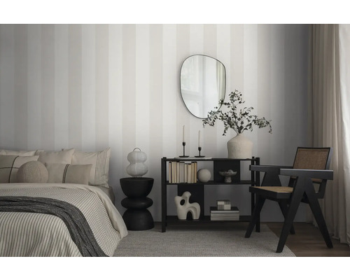 Schlafzimmer mit Bett, Regal, Sessel und gestreifter Tapete