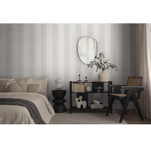 Schlafzimmer mit Bett, Regal, Spiegel und gestreifter Tapete.