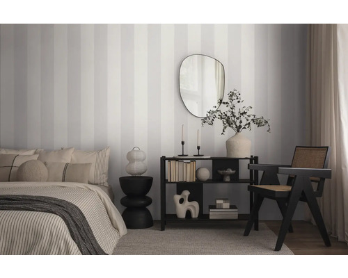 Schlafzimmer mit Bett, Regal, Spiegel und gestreifter Tapete.