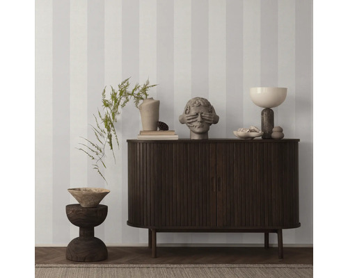 Dekoratives Interieur mit gestreifter Tapete, Kommode, Hocker und Dekorationsgegenständen