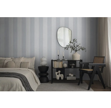 Schlafzimmer mit Bett, Kommode, Spiegel und Stuhl vor gestreifter Tapete.