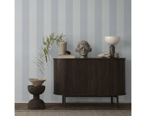 Dekoriertes Sideboard vor gestreifter Tapete