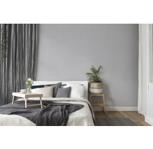 Schlafzimmer mit Bett, Nachttisch, Zimmerpflanze und Vorhängen