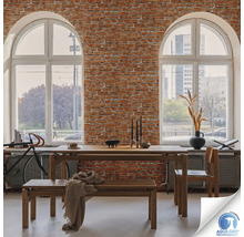 Salle à manger avec table en bois, banc et chaise devant un mur de briques avec deux grandes fenêtres