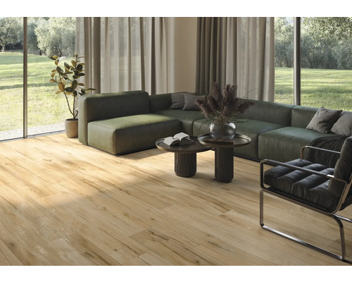 Séjour lumineux avec carrelage imitation bois, canapé, fauteuil et baie vitrée.