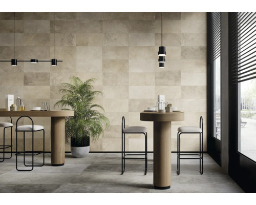 Heller Raum mit Bodenfliesen und Wandfliesen in Natursteinoptik, Tischen und Stühlen