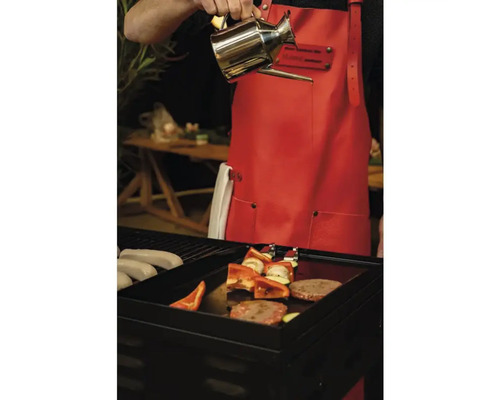 Personne versant de l''huile sur un barbecue avec des saucisses, des légumes et de la viande