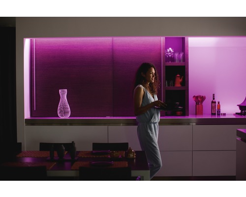 Femme avec des assiettes dans une cuisine moderne avec éclairage décoratif