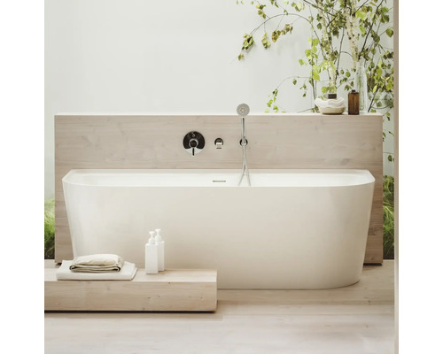 Baignoire îlot avec robinetterie et douchette à main dans une salle de bain lumineuse.