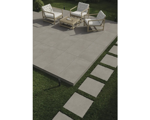 Terrasse avec salon de jardin et dalles carrées en pierre sur gazon