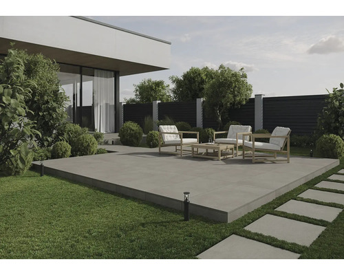 Terrasse avec mobilier de jardin et dalles en pierre dans un jardin moderne.