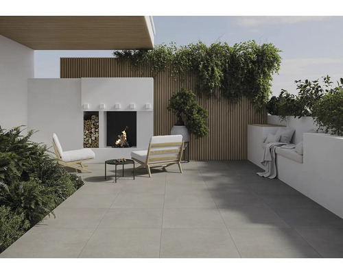 Terrasse avec sol en pierre, sièges, cheminée et plantes pour une ambiance extérieure chaleureuse