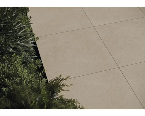 Dalles de terrasse posées à côté de plantations à l''extérieur.