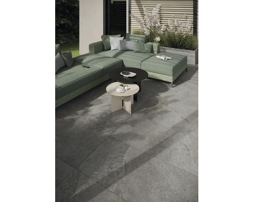 Extérieur avec canapé modulable, deux tables d''appoint rondes et carrelage au sol.