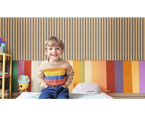 Un enfant est assis devant un mur avec des panneaux de bois et des surfaces colorées