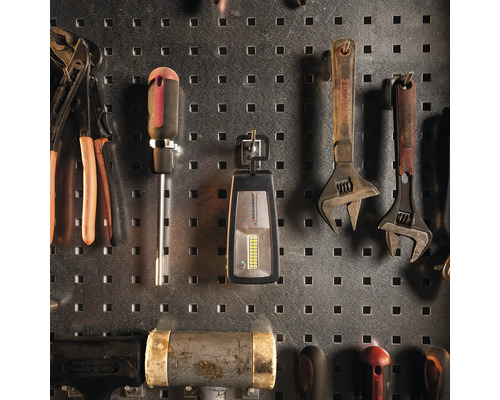 Werkzeuge wie Schraubenschlüssel, Schraubendreher und Zangen an einer Werkzeugwand