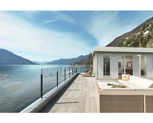Pavillon de jardin avec garde-corps en verre et meubles de salon sur une terrasse avec vue sur le lac