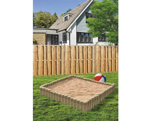 Bac à sable dans le jardin avec clôture en bois et maison à l''arrière-plan