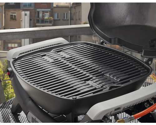 Weber Gasgrill mit Grillrost und geöffnetem Deckel auf einem Balkon