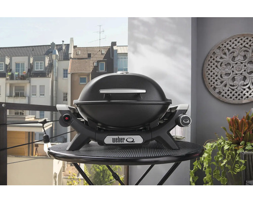 Weber Q Grill auf einem Tisch mit Gebäuden im Hintergrund
