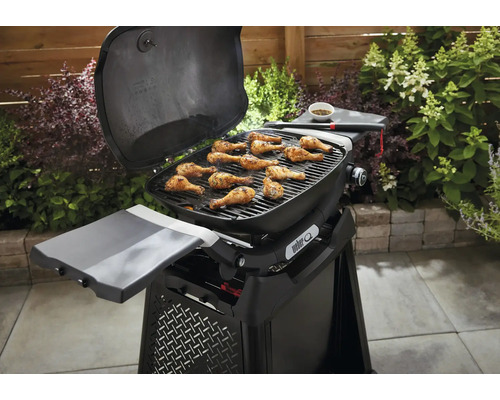 Grill mit Hähnchenschenkeln auf dem Rost im Garten