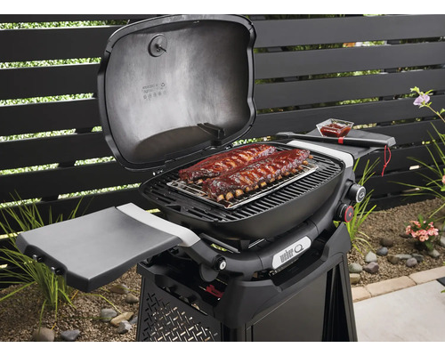 Weber Gasgrill mit Rippchen auf dem Grillrost, inklusive Seitenablage.