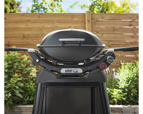 Schwarzer Weber Q Grill mit Gestell vor einem Gartenzaun