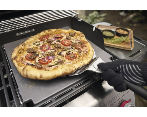 Pizza mit Tomaten, Zwiebeln und Pilzen auf einem Pizzaschieber auf einem Grill.