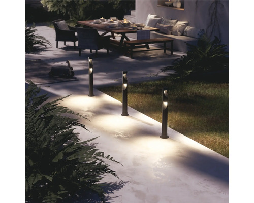 Beleuchtete Gartenanlage mit mehreren Wegeleuchten, Terrassenmöbeln und Bepflanzung.