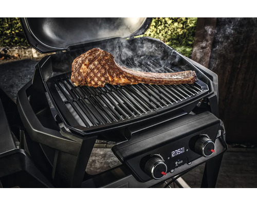 Offener Grill mit einem grossen Tomahawk Steak auf dem Rost.