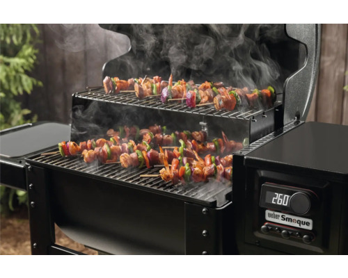 Holzkohlegrill mit Grillspießen und Rauchentwicklung