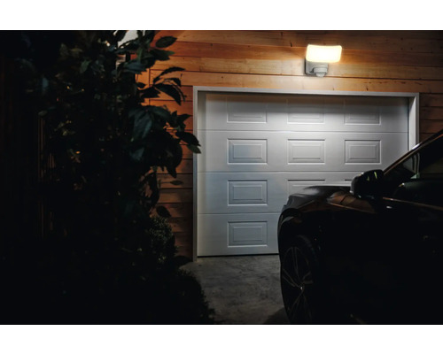 Garage avec porte sectionnelle, éclairée par un luminaire extérieur avec détecteur de mouvement