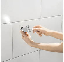 Person montiert einen Handtuchhalter an einer gefliesten Wand