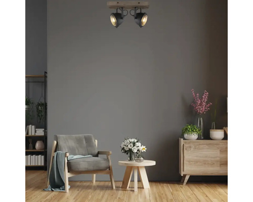 Wohnzimmer mit Sessel, Kommode und Deckenleuchte mit zwei Strahlern