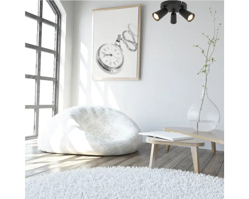 Pièce lumineuse avec pouf, tapis, plafonnier et tableau mural